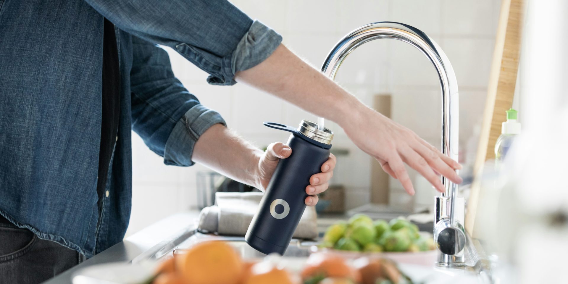 filling-up-water-bottle-from-tap A person is filling up a navy drink bottle with water from the kitchen sink tap.